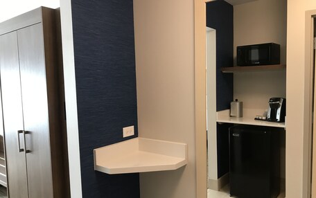 A compact kitchenette with a microwave, coffee maker, and a small shelf.