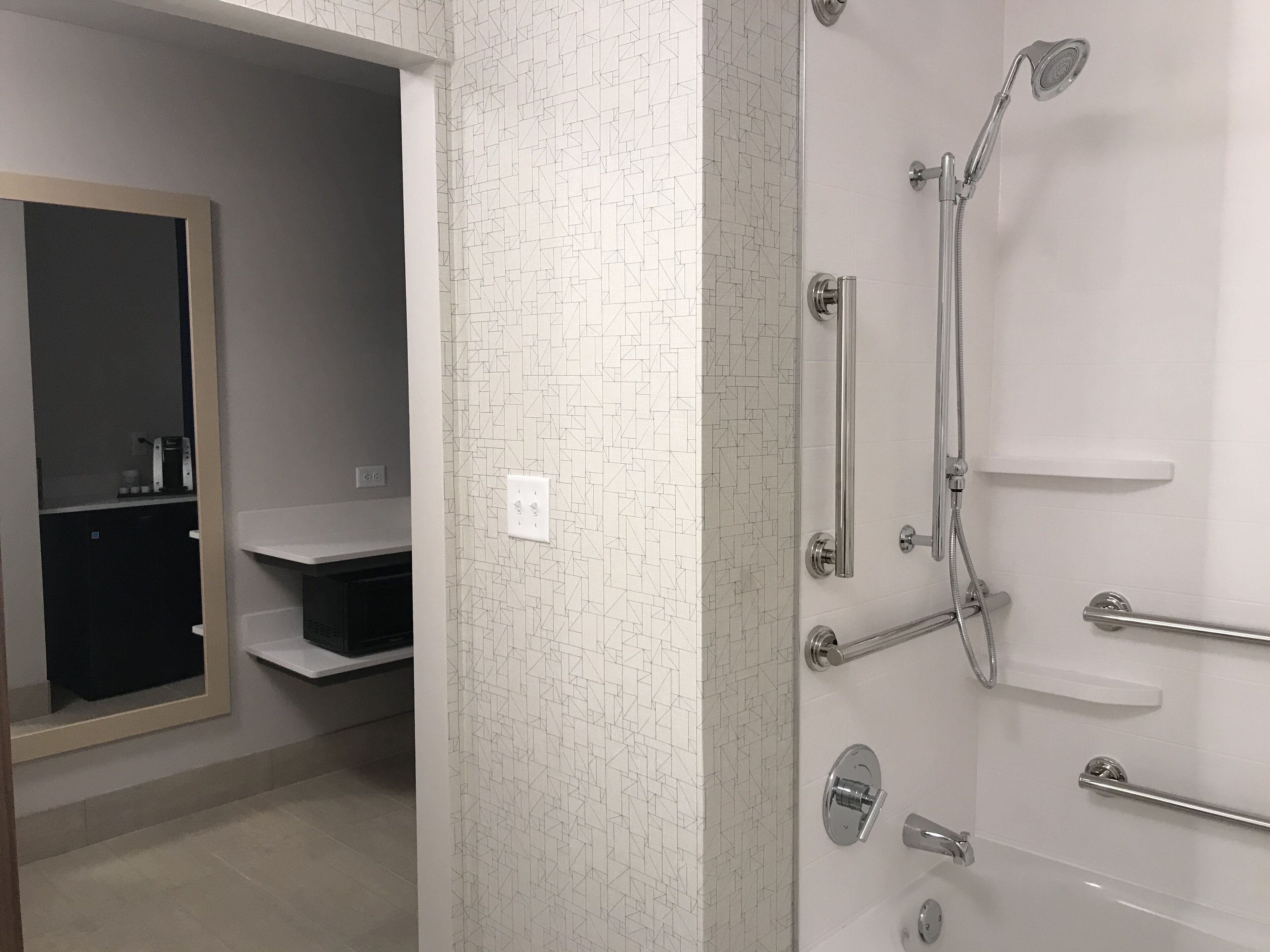A modern bathroom with a shower, a mirror, and a toilet.