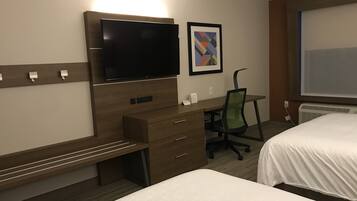 A hotel room with a bed, a desk with a chair, a television, and a framed picture on the wall.