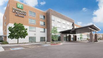 Edificio de Holiday Inn Express & Suites con diseño moderno, entrada cubierta y estacionamiento con acceso para discapacitados.