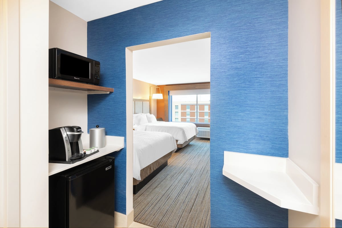 A hotel room with a kitchenette, a bed, and a view of the outside.