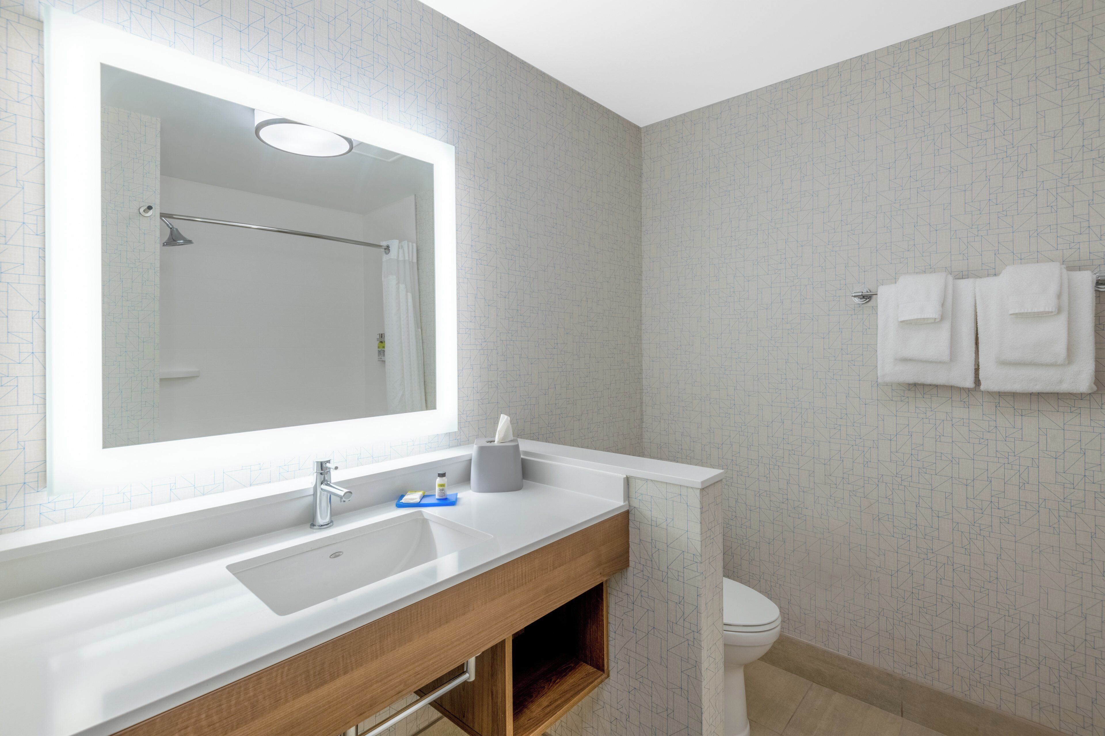 Un baño moderno con un espejo grande, un lavabo y un inodoro.