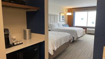 Une chambre d’hôtel avec une kitchenette, deux lits, une grande fenêtre et une vue sur la ville.