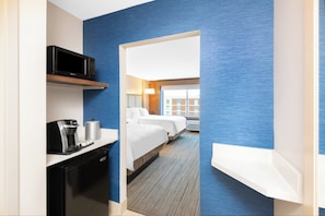 A hotel room with a kitchenette, a bed, a desk, and a view of the outside. - Holiday Inn Express & Suites Phoenix - Airport North by IHG (Phoenix)