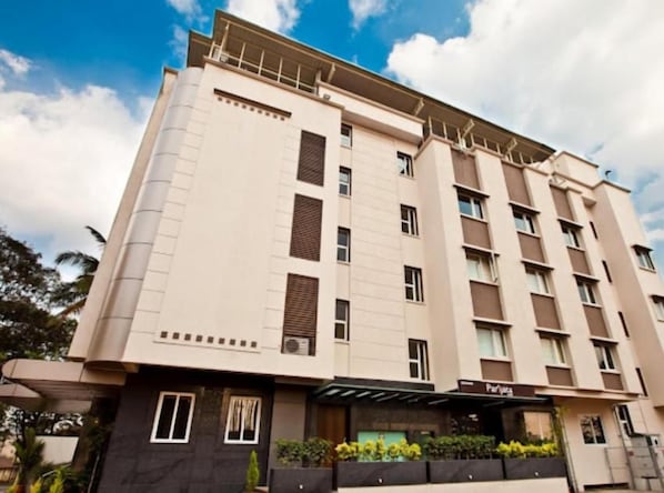 A multi-story hotel with a flat facade, large windows, and a covered entrance area. - Mallige Residency (Hassan)