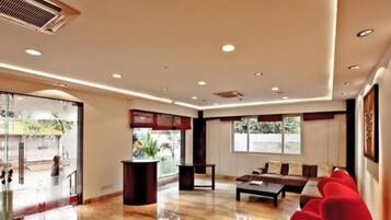 A modern hotel lobby with a reception desk, seating area, and large windows.