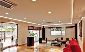 A modern hotel lobby with a reception desk, seating area, and large windows. - Mallige Residency (Hassan)