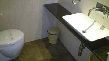 A small bathroom with a white toilet, a sink with a black countertop, and a trash bin.