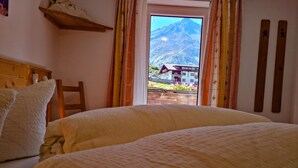 A bedroom with a bed, a wooden chair, and a window with curtains.