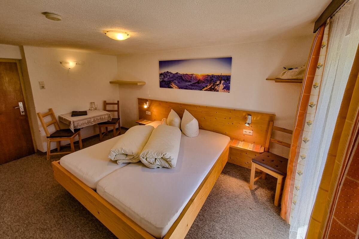A bedroom with a bed, a desk, a chair, and a painting on the wall.