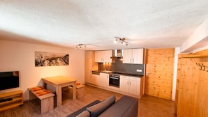 A compact living space with a kitchenette, a sofa, a dining table, and a TV.