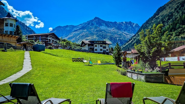 A grassy area with two lounge chairs, a pathway, and a mountain backdrop.