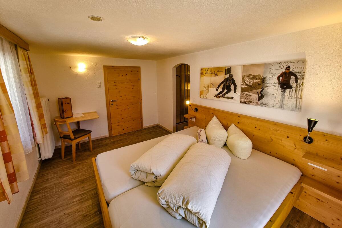 A bedroom with a wooden bed, a desk, and a chair.