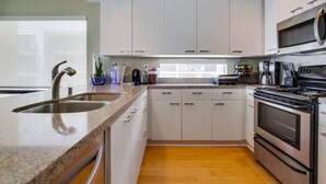 A modern kitchen with a granite countertop, stainless steel sink, and a built-in oven. - 3rd fl. Bayfront condo, balcony, parking, bikes (San Diego)