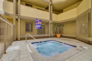 An indoor swimming pool with a safety railing, a potted plant, and a caution sign on the wall.
