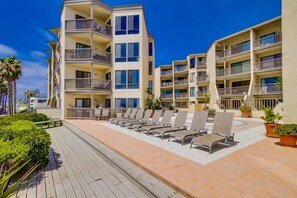 Un hôtel à plusieurs étages doté de balcons, d’un espace piscine avec des chaises longues et d’une promenade en bois.