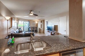 A modern kitchen with granite countertops, stainless steel sink, and a built-in dishwasher.