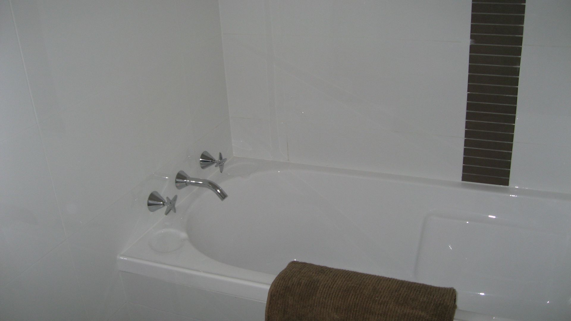 A bathtub with a handheld showerhead and a towel.
