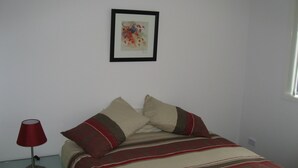 Une chambre à coucher avec un lit, des oreillers, une lampe et un tableau encadré accroché au mur.