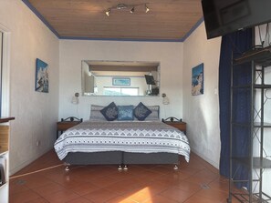 Una camera da letto con un letto, uno specchio grande, una TV e una finestra.