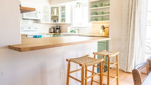 A kitchen with white cabinets, a wooden countertop, and two wicker stools. - Bright family friendly 3 bed 2 bath w/3 king beds located near AFA (Colorado Springs)