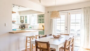 A bright kitchen with white cabinets, a wooden dining table, wicker chairs, and a hanging light fixture. - Bright family friendly 3 bed 2 bath w/3 king beds located near AFA (Colorado Springs)