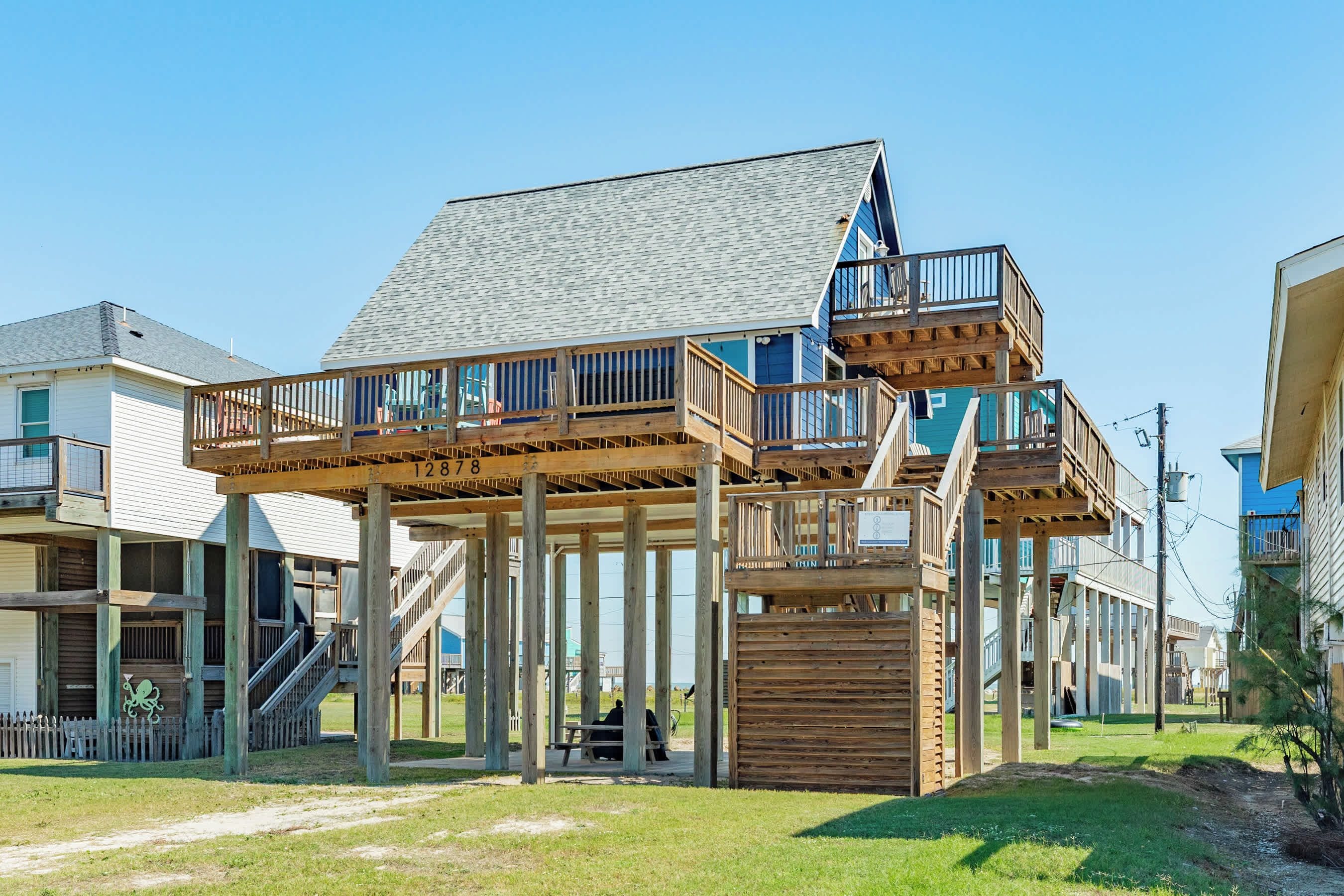 A multi-level wooden structure with a balcony, stairs, and a covered seating area.
