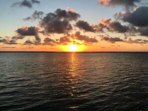Tramonto sul mare calmo, con nuvole nel cielo.