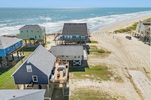 A beachfront property with multiple houses, some elevated on stilts, and a sandy beach in the background. - Across the Pass - Pick Your Sunrise or Sunset Sea! (Freeport)