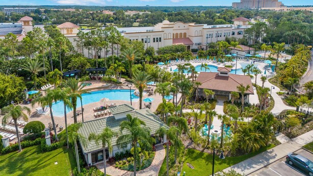 A resort with multiple swimming pools, palm trees, and a large building in the background.