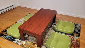 Een houten tafel met vier groene, beklede stoelen op een getextureerd vloerkleed.