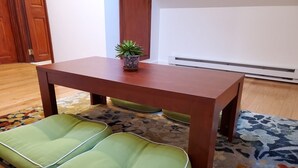 Een houten tafel met twee stoelen met groene kussens.