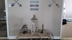A room with a wall-mounted sign with paddles and motivational phrases, a lantern, and a rustic wooden chest.