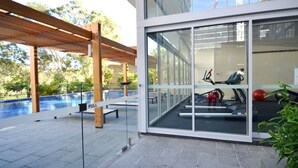 A modern outdoor gym area with exercise equipment, a pull station, and a pool.