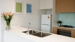 A modern kitchen with a stainless steel sink, a white refrigerator, wooden cabinets, and a gas stove.