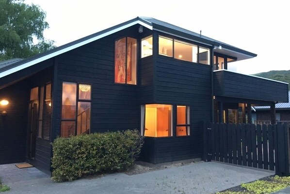 A modern two-story house with large windows and a dark exterior.