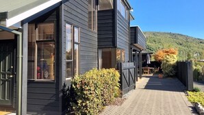 A two-story house with a dark exterior, a covered patio, and a view of a hill. - “CedarView at Kinloch” - a brilliant 3 bedroom holiday home with stunning views  (Kinloch)