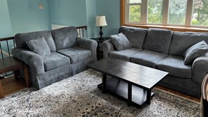 A living room with two grey sofas, a wooden coffee table, and a patterned rug.
