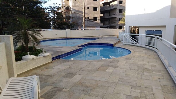 Ein Schwimmbecken mit einer gefliesten Terrasse, umgeben von einer weißen Brüstung.