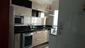 Eine moderne Küche mit Einbau-Mikrowelle, Backofen und Gaskochfeld. Ein Spülbecken mit Armatur sowie Schränke über der Arbeitsplatte sind vorhanden. Am Spülbecken befindet sich ein an der Wand montiertes Telefon.