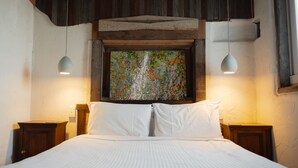 A bedroom with a bed, two bedside tables, a wooden headboard, and a colorful abstract painting above the bed.