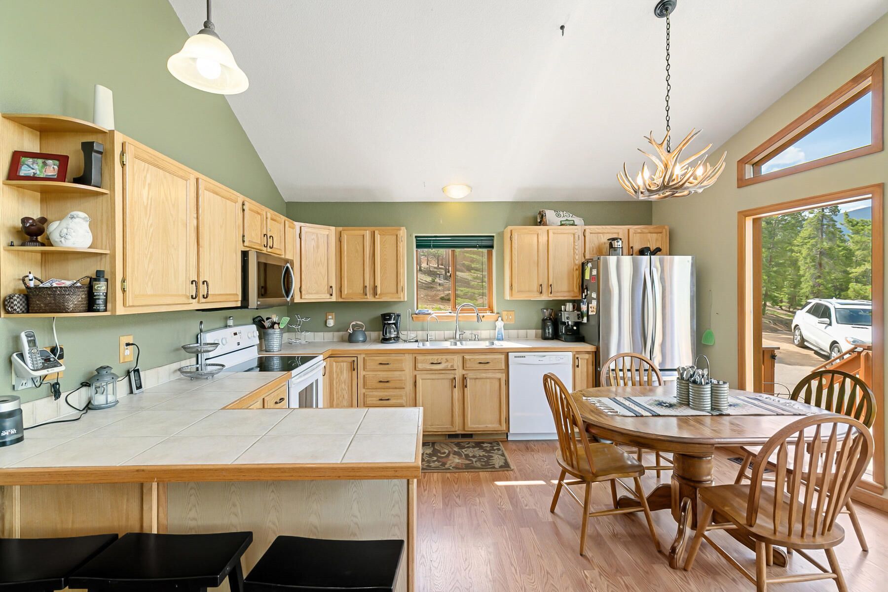 A modern kitchen with wooden cabinets, a central island, and a dining area with wooden chairs.