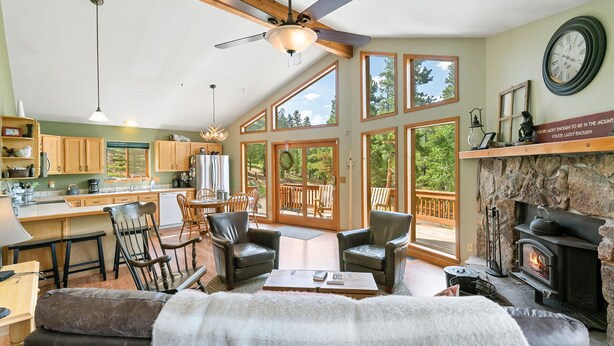 A spacious living area with a fireplace, a dining area, and a kitchen with large windows. - Escape to the Rockies!  3BR Cabin with Outdoor Space, Espresso Machine & Games!! (Bailey)