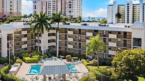 Un hôtel à plusieurs étages doté d’une piscine, d’un court de tennis et d’un aménagement paysager luxuriant.