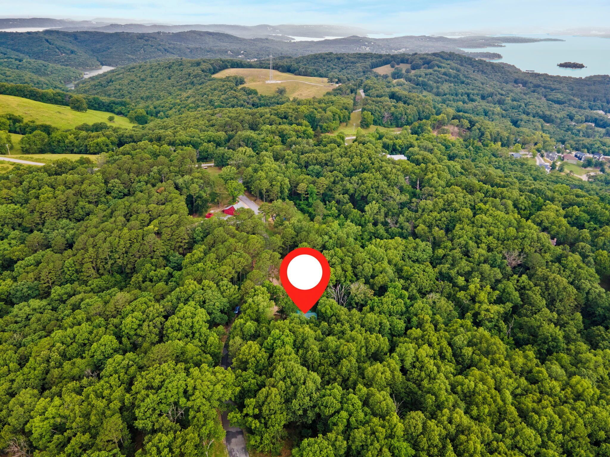 Vista aérea de una zona boscosa con un marcador rojo que indica una ubicación.