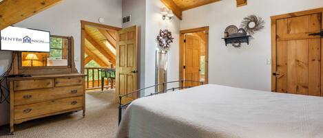 A bedroom with a bed, dresser, ceiling fan, and a view of the outdoors.