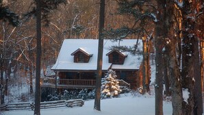 A log cabin with a snow-covered roof, surrounded by trees and a wooden deck. - Private Engleman Spruce Cabin with Game Room, Community Pool & Car Charger (Blue Eye)