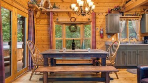 A wooden cabin interior with a dining table, chairs, a chandelier, and a kitchen area. - Private Engleman Spruce Cabin with Game Room, Community Pool & Car Charger (Blue Eye)