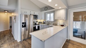A modern kitchen with white cabinetry, stainless steel appliances, and a large island.