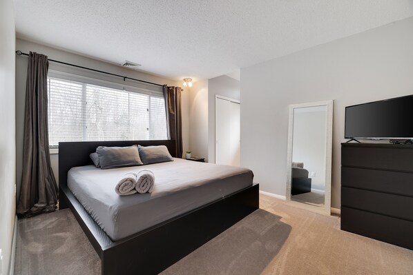 A modern bedroom with a large bed, a TV, and a wardrobe.